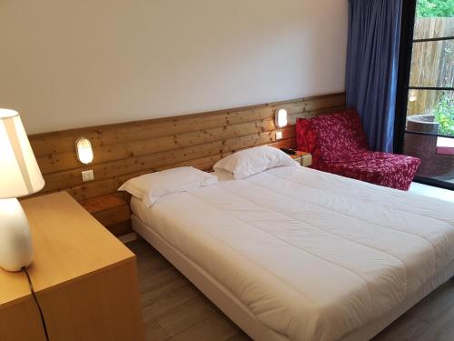 a bedroom with a large bed and a red chair at Le Vieux Logis de Clam in Clam