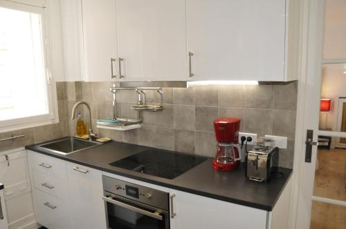 a kitchen with white cabinets and a red blender on a counter at Paris Besson Stay Appartement Neuilly sur Seine in Neuilly-sur-Seine