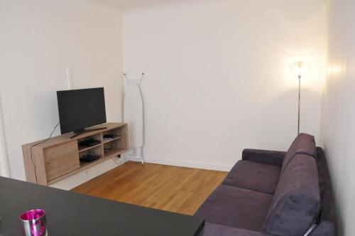 a living room with a couch and a tv at Paris Besson Stay Appartement Neuilly sur Seine in Neuilly-sur-Seine