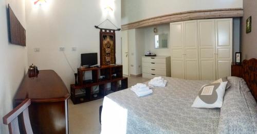 een slaapkamer met een bed, een bureau en een televisie bij B&B Aquilegia in Acqualagna
