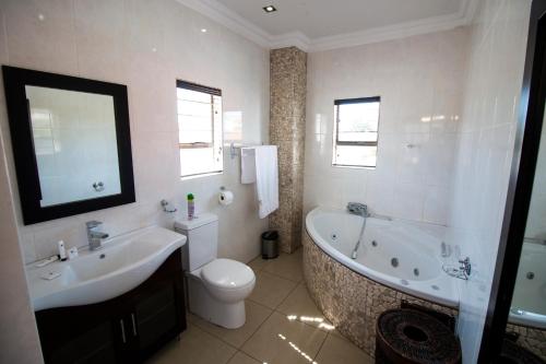 ein Badezimmer mit einer Badewanne, einem WC und einem Waschbecken in der Unterkunft The Shamrock Hotel in Polokwane