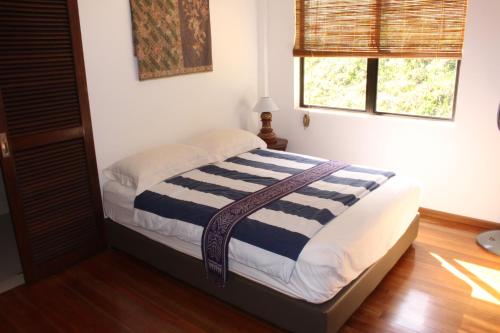 a bedroom with a bed with a striped blanket at Nanga Damai Homestay in Santubong