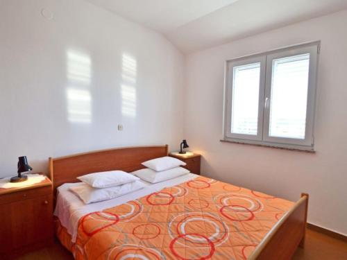 a bedroom with a large orange bed with two windows at Apartments Milin in Božava