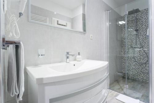 een witte badkamer met een wastafel en een douche bij Luxury Rooms Floramye in Split