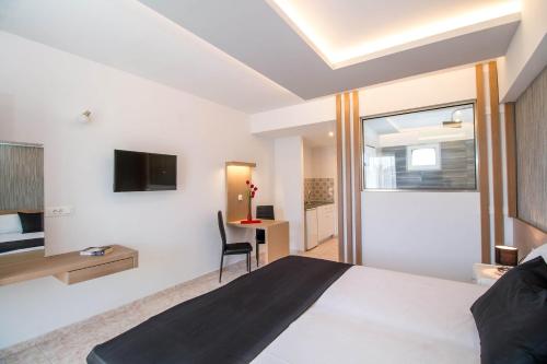 CasaStavris - Aparts & Pool Suites في فاليراكي: غرفة نوم بسرير ومكتب وتلفزيون