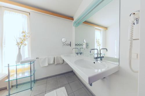 
a bathroom with a sink, mirror, and bathtub at Hotel Klinglhuber in Krems an der Donau
