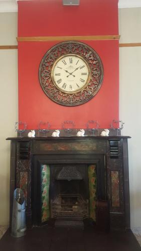 a clock on a wall above a fireplace at Oregon Cottage in Ficksburg