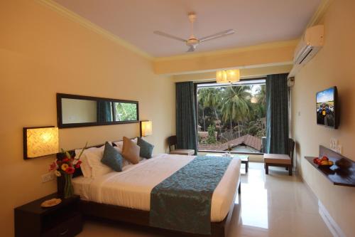 a bedroom with a large bed and a large window at De Baga Deck Comforts in Calangute