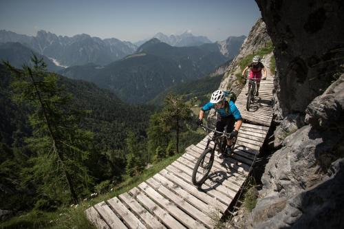 two people riding bikes on a wooden trail in the mountains at Sölle Homes Nassfeld in Sonnenalpe Nassfeld