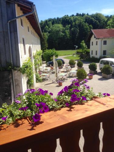 a balcony with purple flowers and a patio with tables at Pension Poschmühle in Traunreut