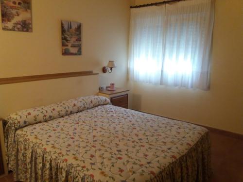 1 dormitorio con cama y ventana en Apartamentos El Cazador, en San Vicente de Toranzo