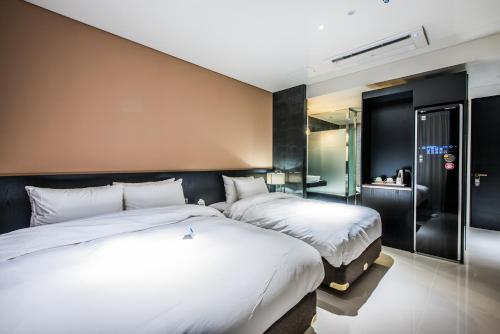 a hotel room with two beds and a bathroom at Rivertain Hotel in Daegu