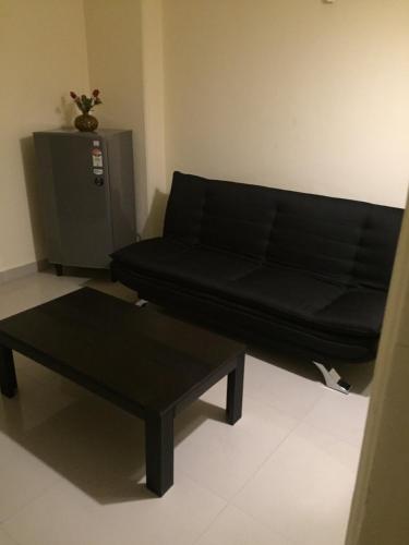a black couch and a table in a room at Aloha Apartments by blissful Ganges in Rishīkesh