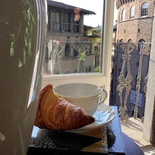 a plate of bread and a cup on a table with a window at Tornabuoni View in Florence