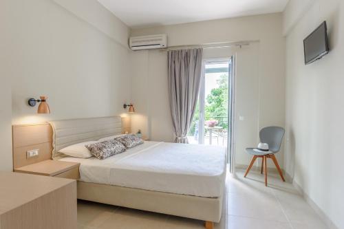 a white bedroom with a bed and a window at Yellow house in Parga