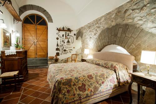 a bedroom with a bed and a stone wall at Antico Casale Ruoppo in SantʼAgata sui Due Golfi