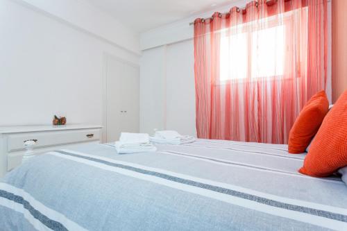 1 dormitorio con 1 cama con almohadas de color naranja y ventana en Apartamento Arenga, en Lagos