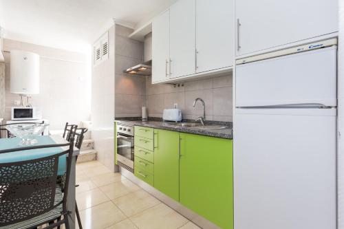 a kitchen with green cabinets and a white refrigerator at Apartamento Arenga in Lagos