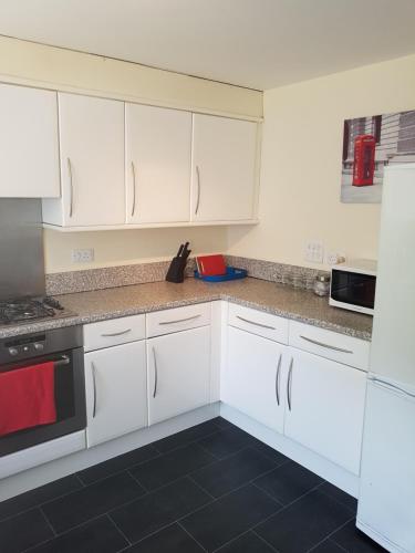 a kitchen with white cabinets and a black tile floor at Livingston 4 bedroom townhouse in Livingston