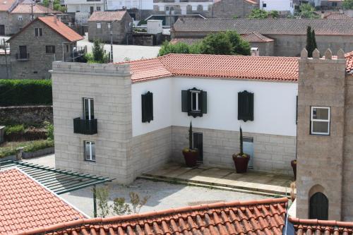 a white house with black shutters on a building at Hotel Medieval® de Penedono in Penedono