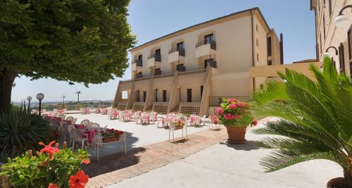 a building with pink tables and chairs in front of it at Hotel Bel Sit in Senigallia