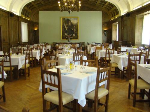 a dining room with white tables and chairs and a chandelier at Hospedería Santa Cruz in San Lorenzo de El Escorial