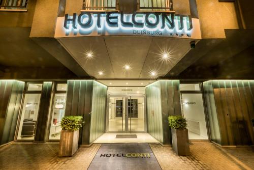 a hotel entrance with two potted plants in front of it at Hotel Conti Duisburg - Partner of SORAT Hotels in Duisburg