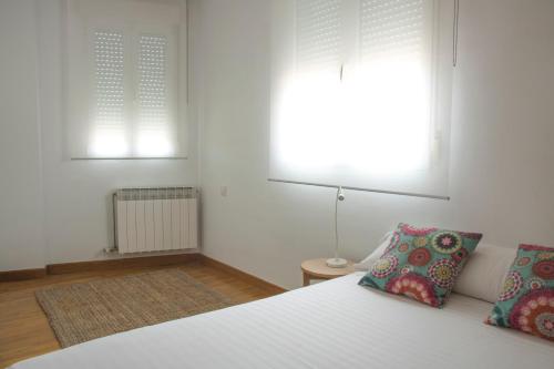 1 Schlafzimmer mit einem weißen Bett und 2 Fenstern in der Unterkunft Vut Duplex La Puebla Parking gratis in Burgos