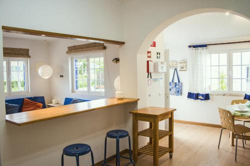 cocina y sala de estar con encimera y taburetes en Casal Do Góis Guest House en Atouguia da Baleia
