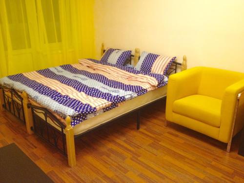 モスクワにあるСовременная квартира с Евроремонтомのベッド1台と黄色い椅子が備わります。