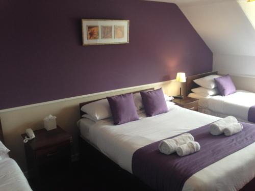 two beds in a hotel room with purple walls at Aberdour Hotel, Stables Rooms & Beer Garden in Aberdour