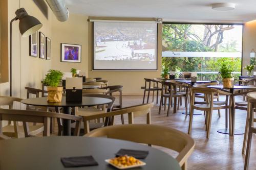a restaurant with tables and chairs and a large screen at Intelier Orange in Benicàssim
