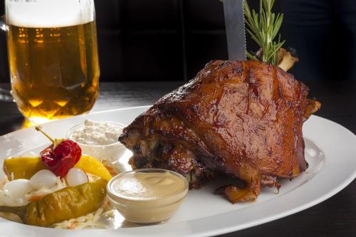 a piece of meat on a plate with a glass of beer at Hotel At the Golden Scissors in Prague