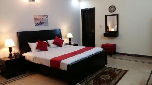 una camera da letto con un letto con cuscini rossi e uno specchio di Serene Residence a Islamabad