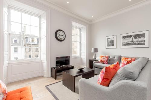 a living room with a couch and a clock on the wall at Destiny Scotland - Chisholm Hunter Suites in Edinburgh