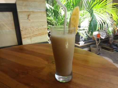 un vaso de zumo de naranja sentado en una mesa de madera en Rumah Ary Homestay & Spa, en Ubud