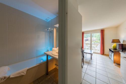 une salle de bain avec une baignoire et un lavabo dans l'établissement Vacancéole - Le Domaine du Golf d'Albret, à Barbaste