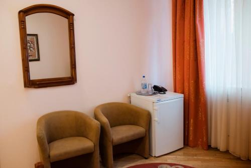 リウネにあるOkolytsyaの椅子2脚、鏡、冷蔵庫が備わる客室です。