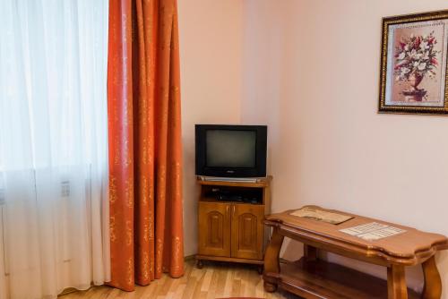 リウネにあるOkolytsyaのテレビ、テーブル、カーテンが備わる客室です。