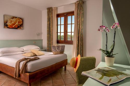 a bedroom with a bed and a table and a window at Tris Hotel in Orbetello