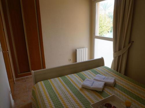 アルビールにあるCharming Apartment in L'Albir with Swimming Poolのベッドルーム1室(窓のあるベッド1台にタオル2枚付)