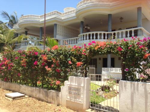 a house with pink flowers in front of a fence at Downtown Malindi Apartment in Malindi