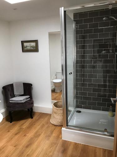 a bathroom with a glass shower and a chair at The Gallery Two Bedroom Apartment in Oakham