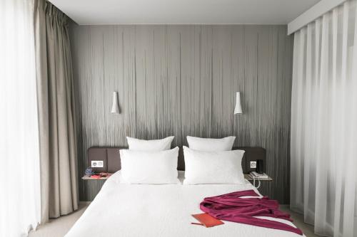 - une chambre avec un grand lit blanc et des oreillers blancs dans l'établissement Okko Hotels Paris Porte De Versailles, à Paris
