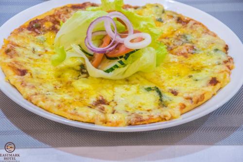 a pizza with lettuce and onions on a white plate at Eastmark Hotel in Nakuru