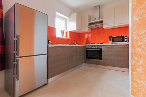 a kitchen with a refrigerator and an orange wall at Apartment Valmas in Pula