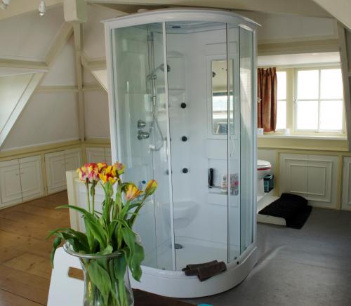 a bathroom with a shower and a vase of flowers at Art+bed and breakfast in 's-Graveland