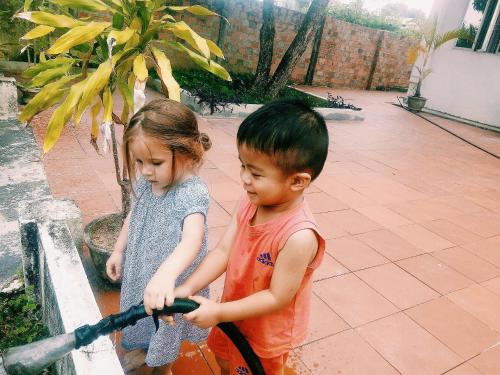 a boy and a girl playing with a water hose at Vietnam Phuot Real Home in Kon Tum