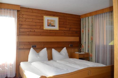 a bedroom with a white bed with a wooden headboard at Pension Bergsee in Sölden