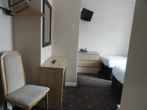 a room with two beds and a desk and a chair at The Beechfield Hotel in Blackpool